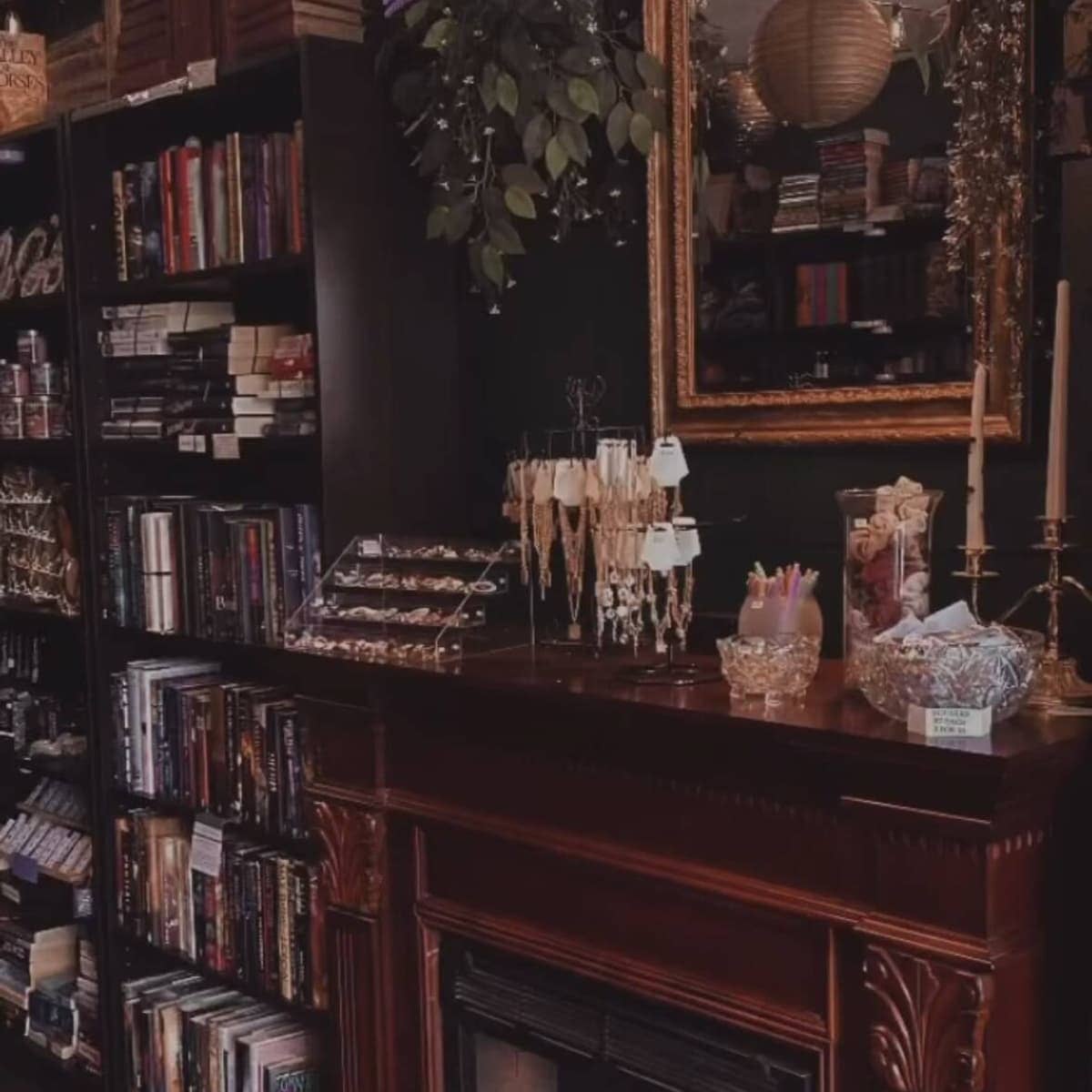 Inside Grimsby Books — dark walls, mahogany mantle, brass candelabra and shelves of fantasy and romance hardcovers.